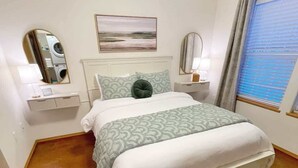 A neatly arranged bedroom with a bed, bedside tables, a mirror, and a window with blinds. - Private & Quiet! 2bd/2ba w/ Laundry & Mt. Views! (Palmer)