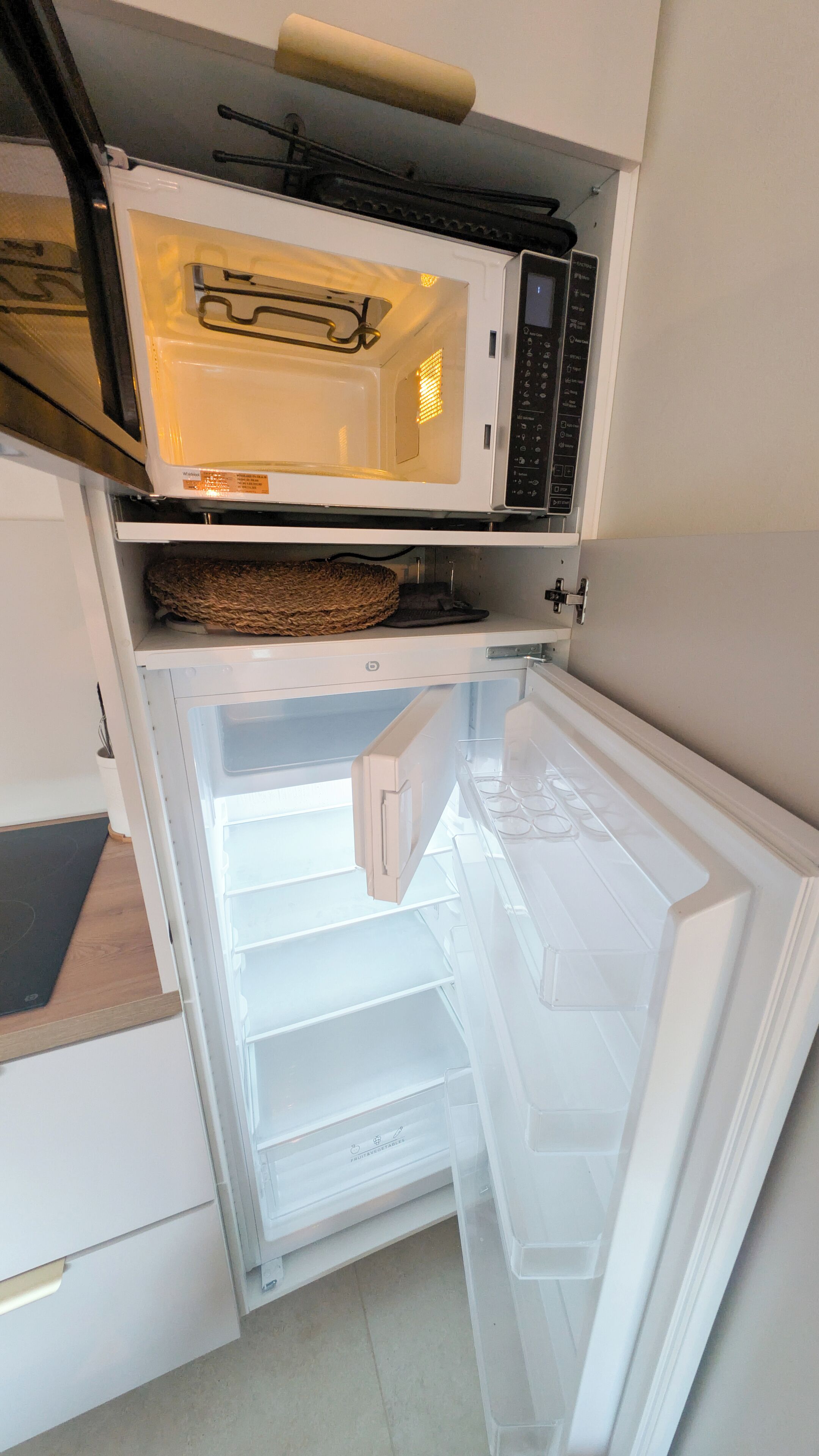 Une cuisine compacte équipée d’un four à micro-ondes et d’un réfrigérateur.