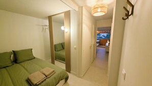 A bedroom with a bed, a mirror, and a hallway leading to a balcony. - Seaside, cosy apartment + parking, facing Santa Lucia harbour (Saint-Raphaël)
