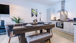 Een moderne keuken met een eettafel voor vier personen, een inbouwoven en een roestvrijstalen afzuigkap.