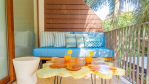 A balcony with a blue sofa, patterned cushions, and two glasses of orange juice on a glass table. - Sunny Studio in Romantic Zone. Steps to Beach. (Puerto Vallarta)