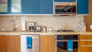 A modern kitchen with blue cabinets, a stainless steel range hood, a dishwasher, and a built-in oven. - Sunny Studio in Romantic Zone. Steps to Beach. (Puerto Vallarta)