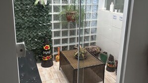 A glass door leading to a patio area with a tiled floor, a wicker table, and various potted plants. - Large house with floor (São Paulo)
