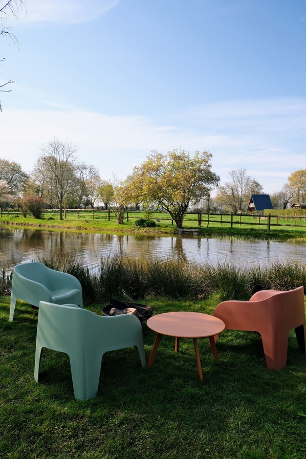 A grassy area with a pond, two chairs, and a small table.