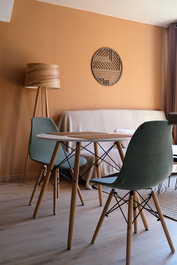 Une pièce comprenant un lit, une table ronde, deux chaises, une lampe sur pied et un élément décoratif mural.
