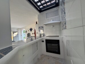 Cocina con horno empotrado, salpicadero de azulejos y una ventana sobre la encimera.