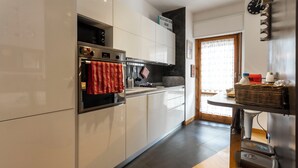 A modern kitchen with white cabinets, a stainless steel oven, and a red towel hanging on the oven handle. - Acasadigiò B&B - 400 meters from the Metro stop and 15 minutes from the center of Rome (Roma)