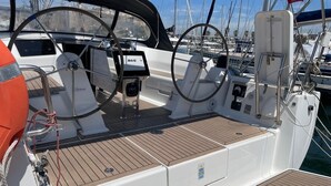 A sailboat's deck with a steering wheel, B&G navigation equipment, and a lifebuoy.