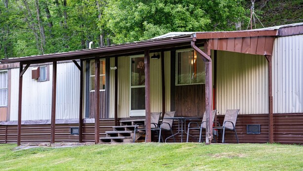 A mobile home with a porch, a table, and chairs.