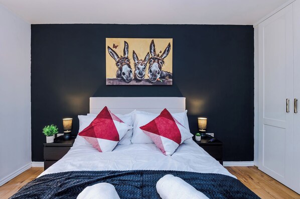 Une chambre à coucher avec un lit, deux tables de chevet, un tableau et une armoire.