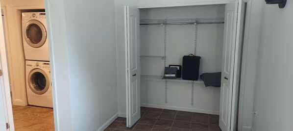 Un cuarto de lavado con lavadora y secadora, un estante metálico y una puerta con manija.