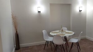 Ein Essbereich mit einem runden Tisch, vier weißen Stühlen und zwei Wandleuchten.