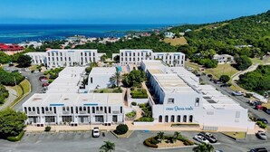 A large, multi-story hotel with a central courtyard, surrounded by lush greenery and a view of the ocean. - Enjoy Passport to Paradise! (Christiansted)