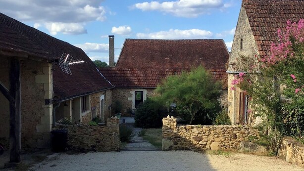 A stone building with a gravel driveway leading to a wooden door.