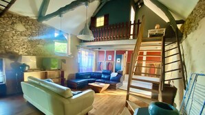 A cozy living room with a white sofa, a blue sectional, and a wooden staircase.