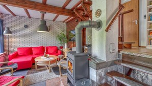 Ein gemütliches Wohnzimmer mit einem roten Sofa, einem runden Holztisch und einem Kamin.