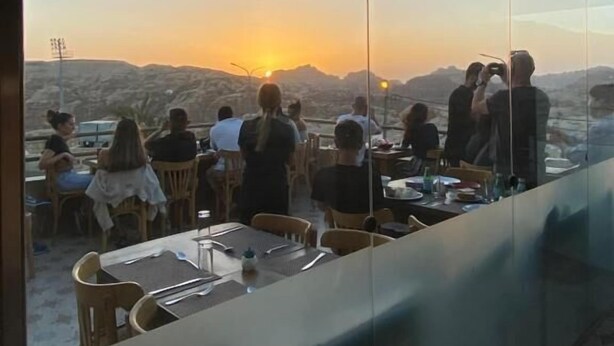 A restaurant with a view of the sunset over mountains. - Petra Jewel Hotel (Wadi Musa)