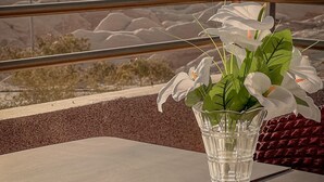 A clear glass vase with white flowers on a table with a view of mountains. - Petra Jewel Hotel (Wadi Musa)