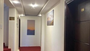 A hallway with a red carpet, white walls, and a black door marked with the number 106. - Petra Jewel Hotel (Wadi Musa)