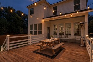 A wooden deck with a picnic table and string lights.