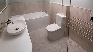 A modern bathroom with a skylight, a freestanding bathtub, a toilet, and a sink.