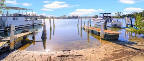 Un rivage paisible, avec des bateaux amarrés à des quais en bois, une plage de sable et un ciel dégagé.