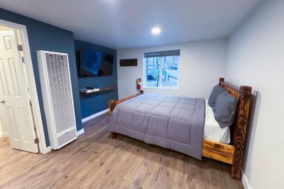 Un dormitorio con cama, ventana, calefactor y puerta.