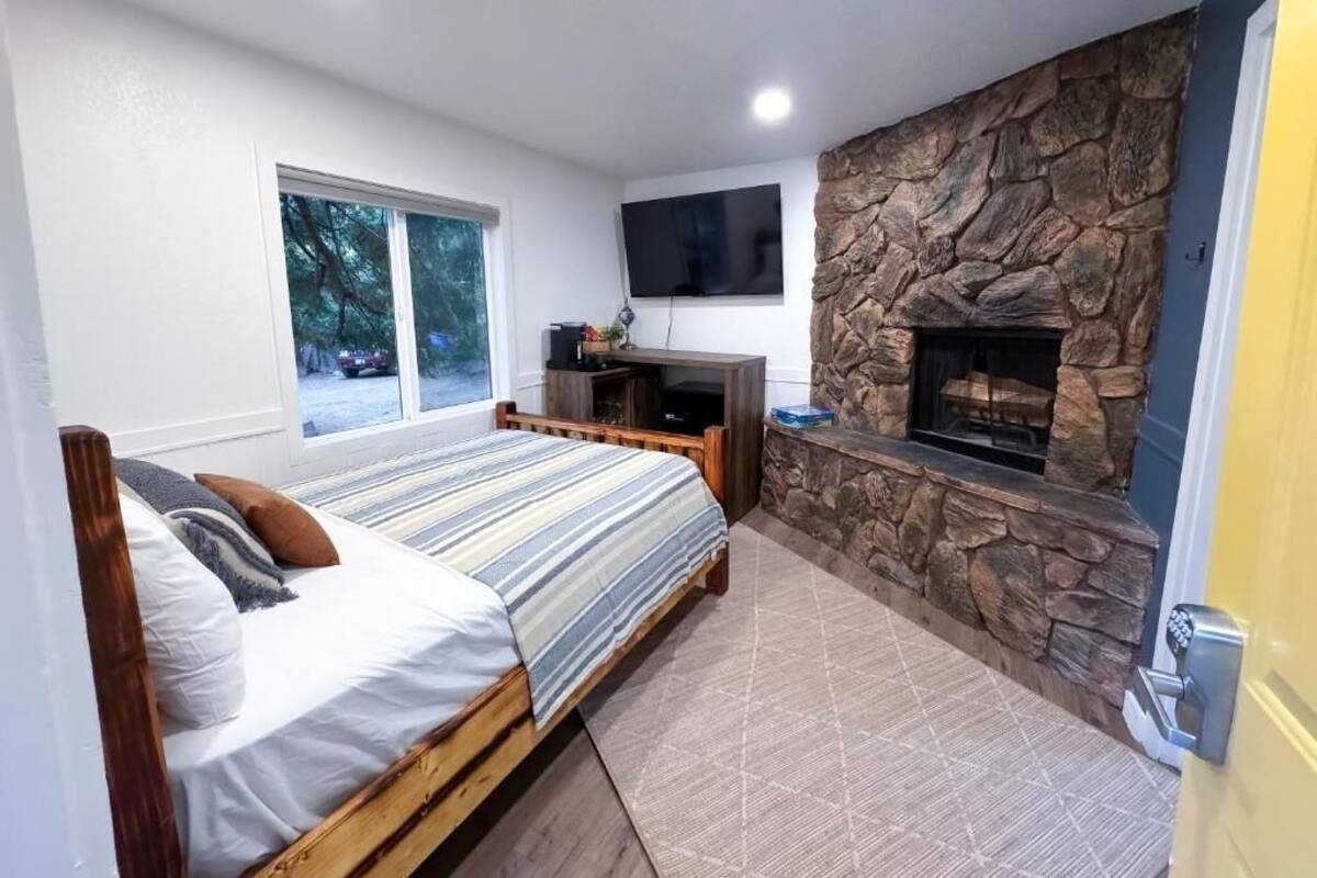 Un dormitorio con cama, televisión, chimenea de piedra y ventana.