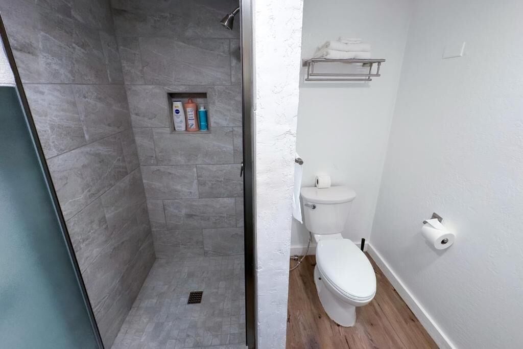 Ein Badezimmer mit Dusche, Toilette und Ablage für Toilettenartikel.