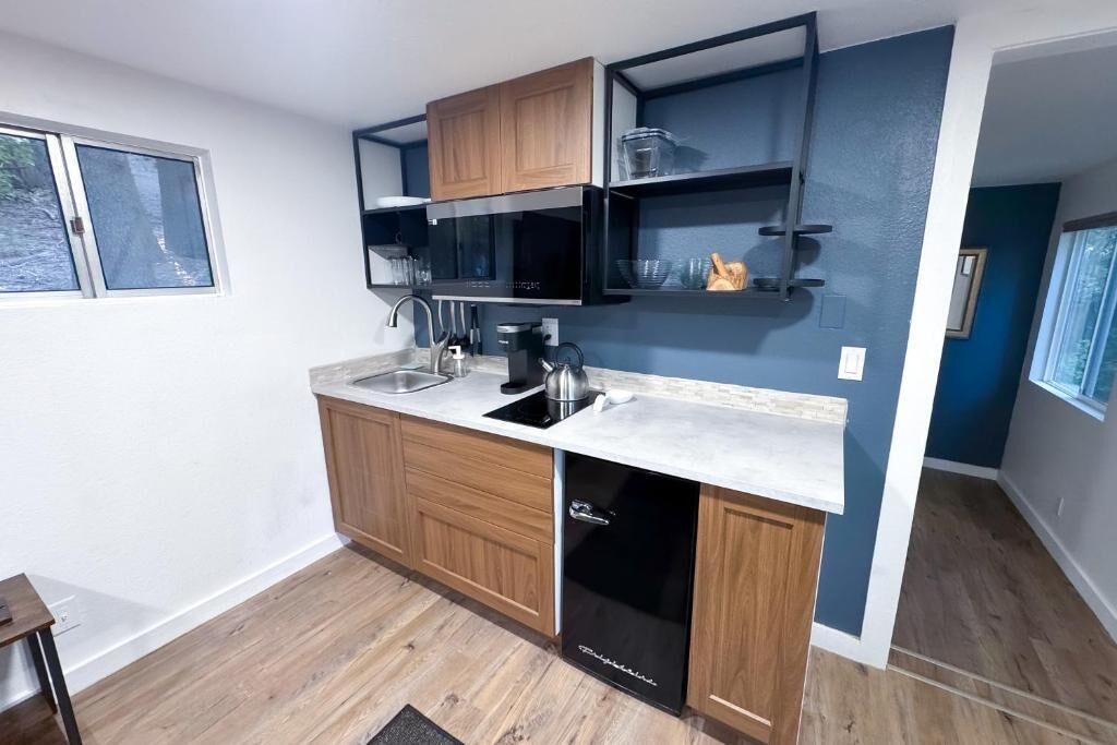 A compact kitchen with wooden cabinets, a black dishwasher, and a countertop with a sink and stove.