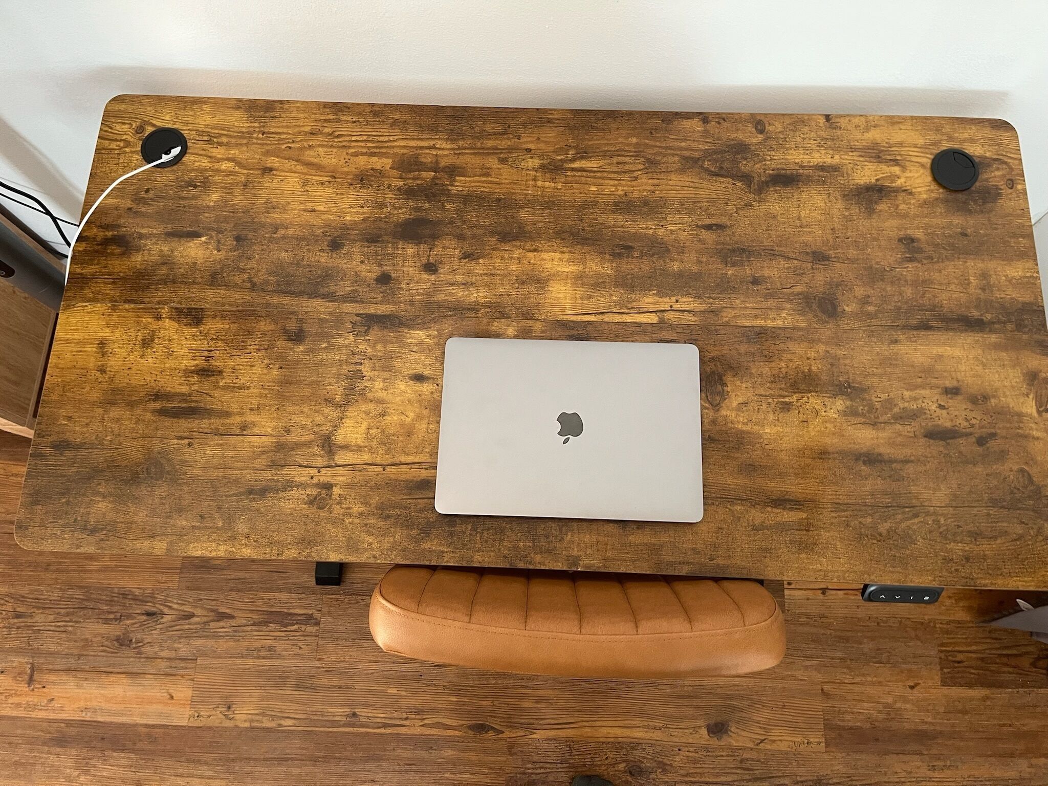 Ein Holztisch mit einem Laptop und einem Lederkissen.