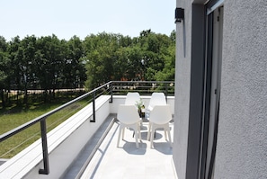 A balcony with white chairs and a table, overlooking a green area with trees. - Luxury Villa Tara, 4 bedroom Villa with heated big pool (Medulin)