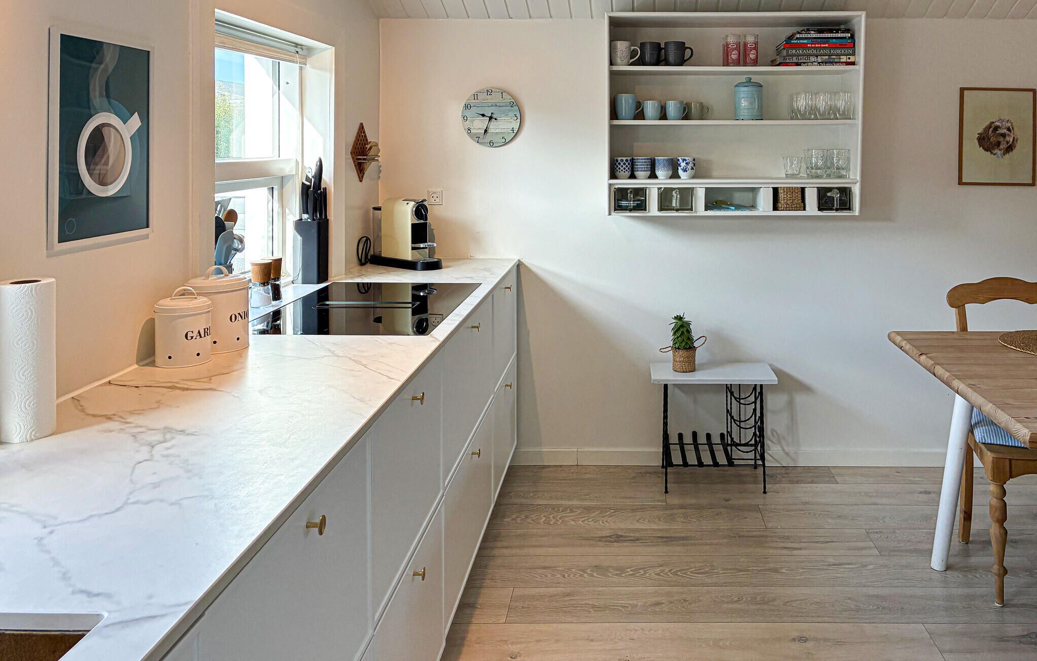 A kitchen with a marble countertop, a coffee machine, and a small table with a plant.