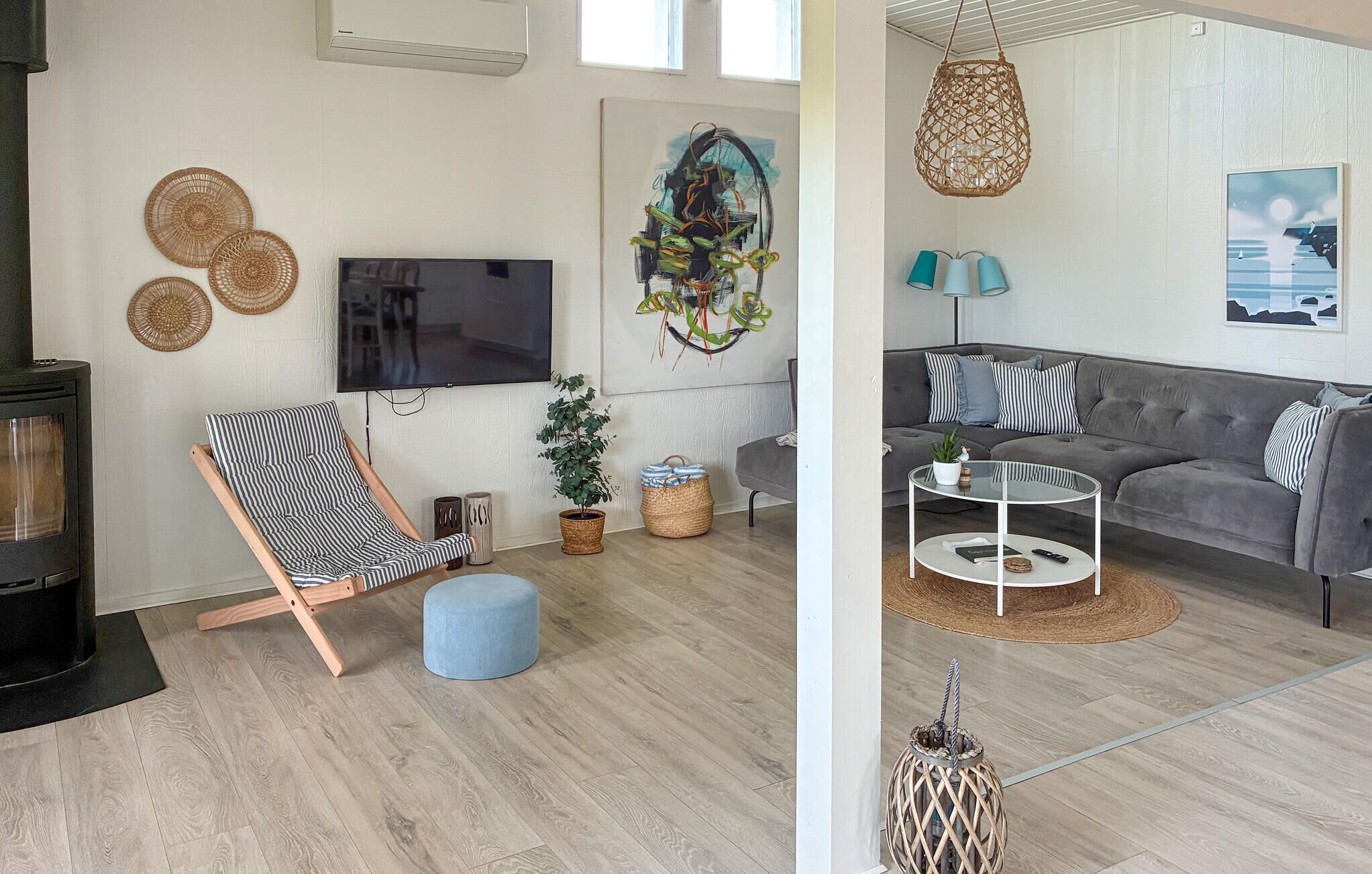 Een woonkamer met een televisie, een bank, een stoel en een open haard.