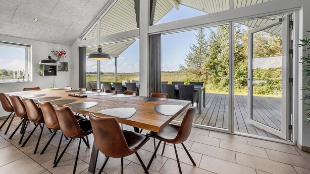 Un vaste espace dédié à la salle à manger, avec une grande table, de nombreuses chaises et une vue sur l’extérieur.