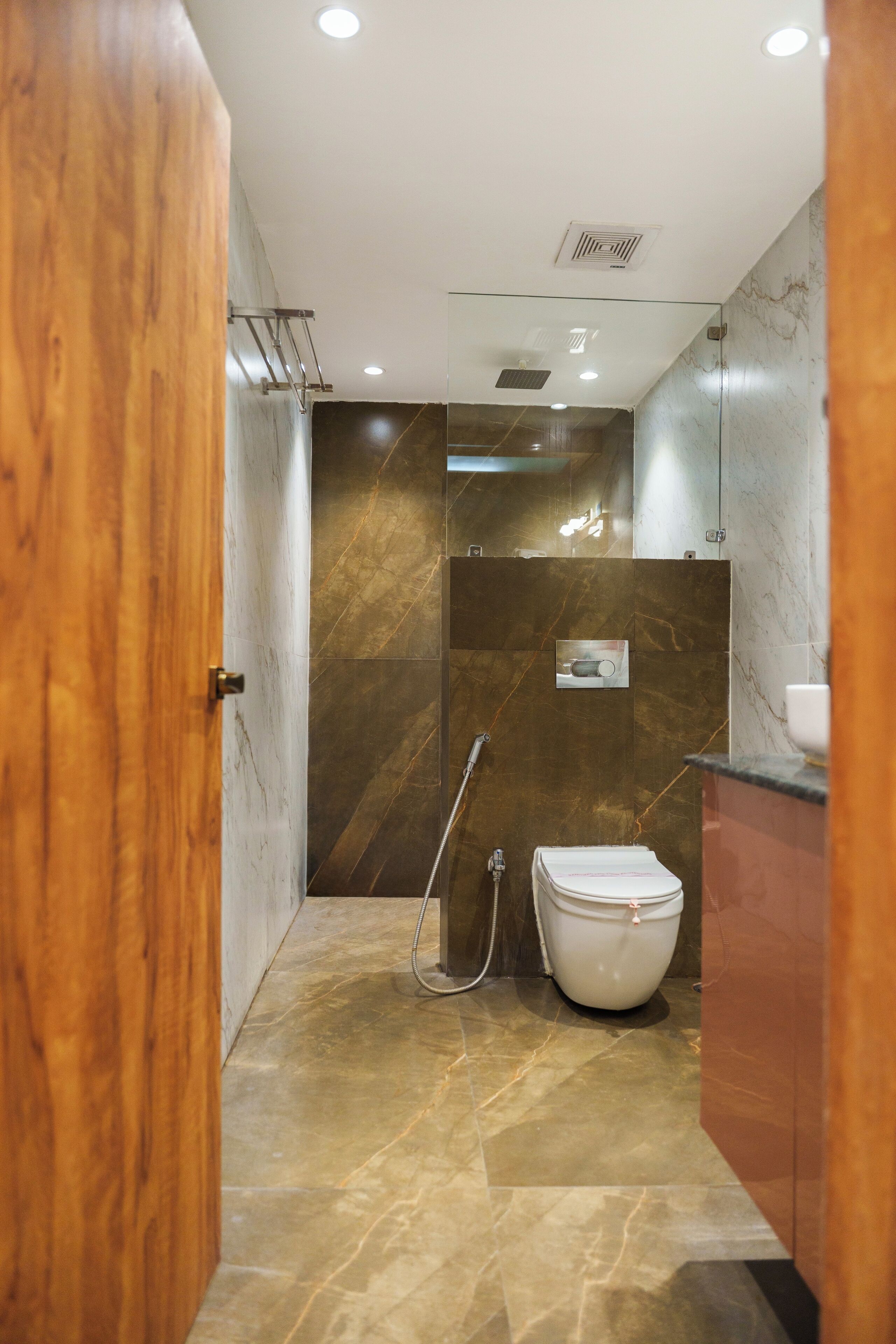 A modern bathroom with a marble floor, a white toilet, and a glass shower enclosure.