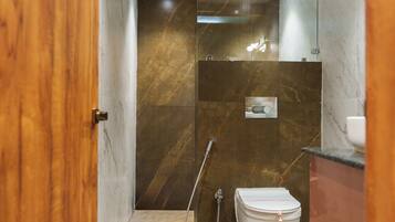 A modern bathroom with a marble floor, a white toilet, and a glass shower enclosure.