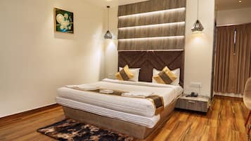 A modern bedroom with a large bed, wooden flooring, and a headboard with built-in lighting.
