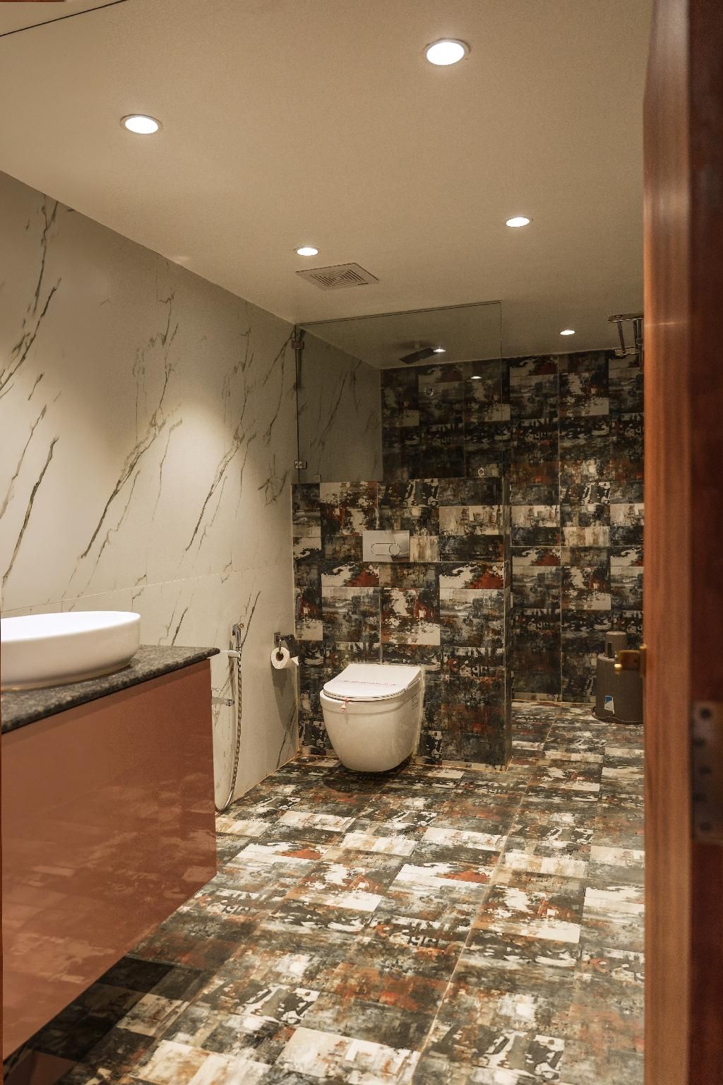 Ein Badezimmer mit Marmorwand, einem Waschbecken, einer Toilette und einer Duschkabine.