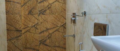 A bathroom with a marble wall, a toilet, and a sink.