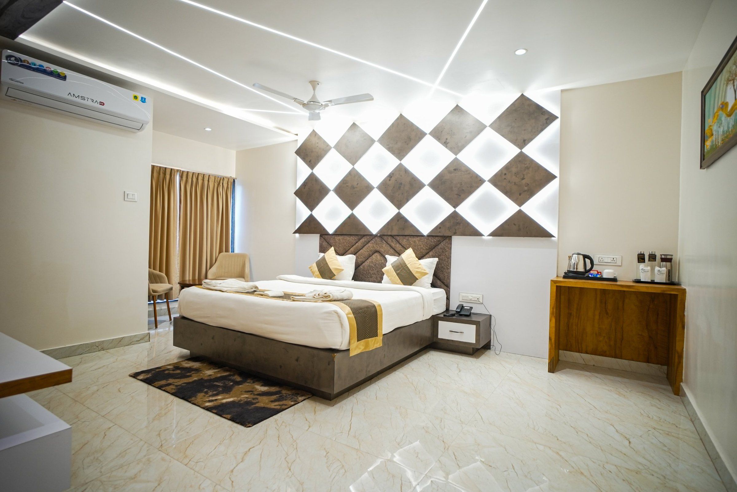 A modern hotel room with a large bed, a bedside table, a nightstand, a ceiling fan, and a wall-mounted air conditioning unit.