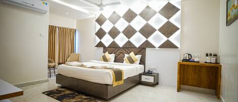 A modern hotel room with a large bed, a bedside table, a nightstand, a ceiling fan, and a wall-mounted air conditioning unit.