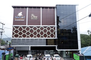 Un edificio de varios pisos con letreros que indican 'Sea Food Delight' y 'Olive Hotel & Suites'.