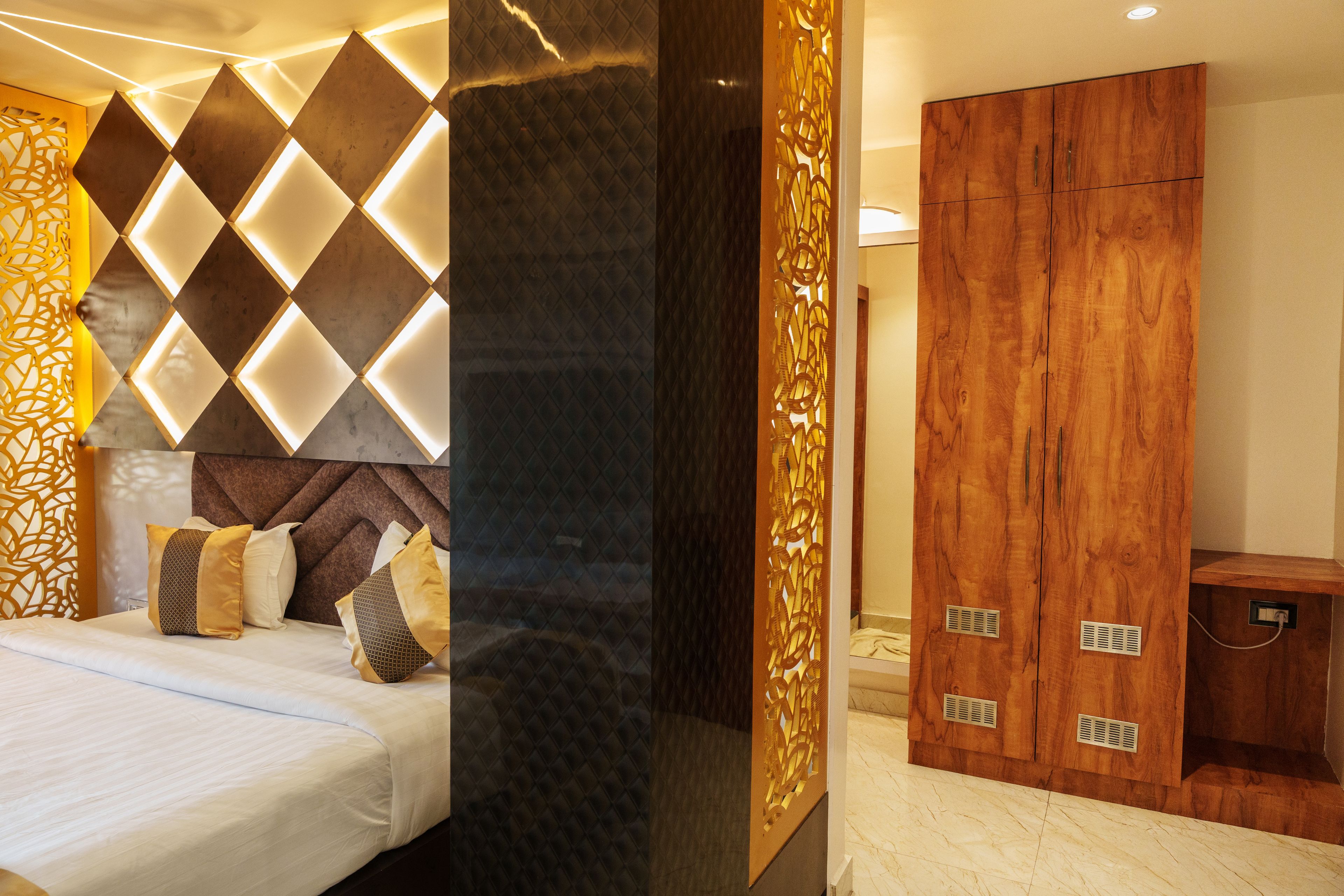 A modern hotel room with a bed, a wooden wardrobe, and a decorative wall panel.