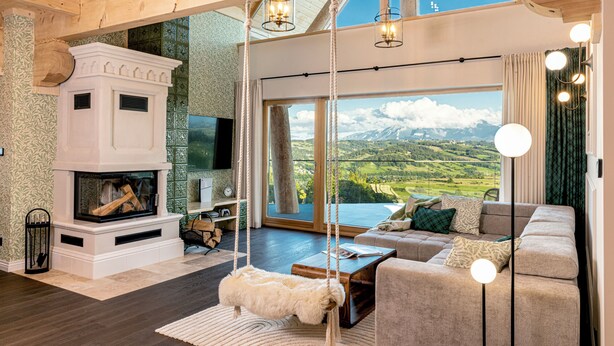A spacious living room with a fireplace, a large sofa, and a hanging swing chair. - Exclusive Villa for Family, Friends & Workation (Biały Dunajec)