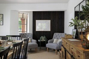 A modern living room with two grey armchairs, a wooden coffee table, and a map on the wall.