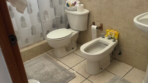 Ein Badezimmer mit Toilette, Bidet, Waschbecken und einem Fenster.