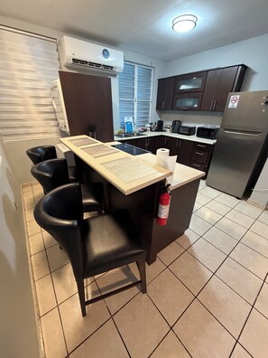 A compact kitchen with a central island, a built-in stove, a microwave, a refrigerator, and a fire extinguisher. - 3-bedroom house in enjoyable Sabana Hoyos with AC (Sabana Hoyos)