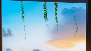 Una mesa y sillas de madera en un balcón con vista al mar y al atardecer.