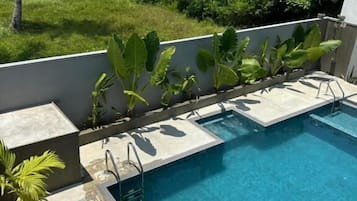 Een buitenzwembad, parasols bij het zwembad en ligstoelen